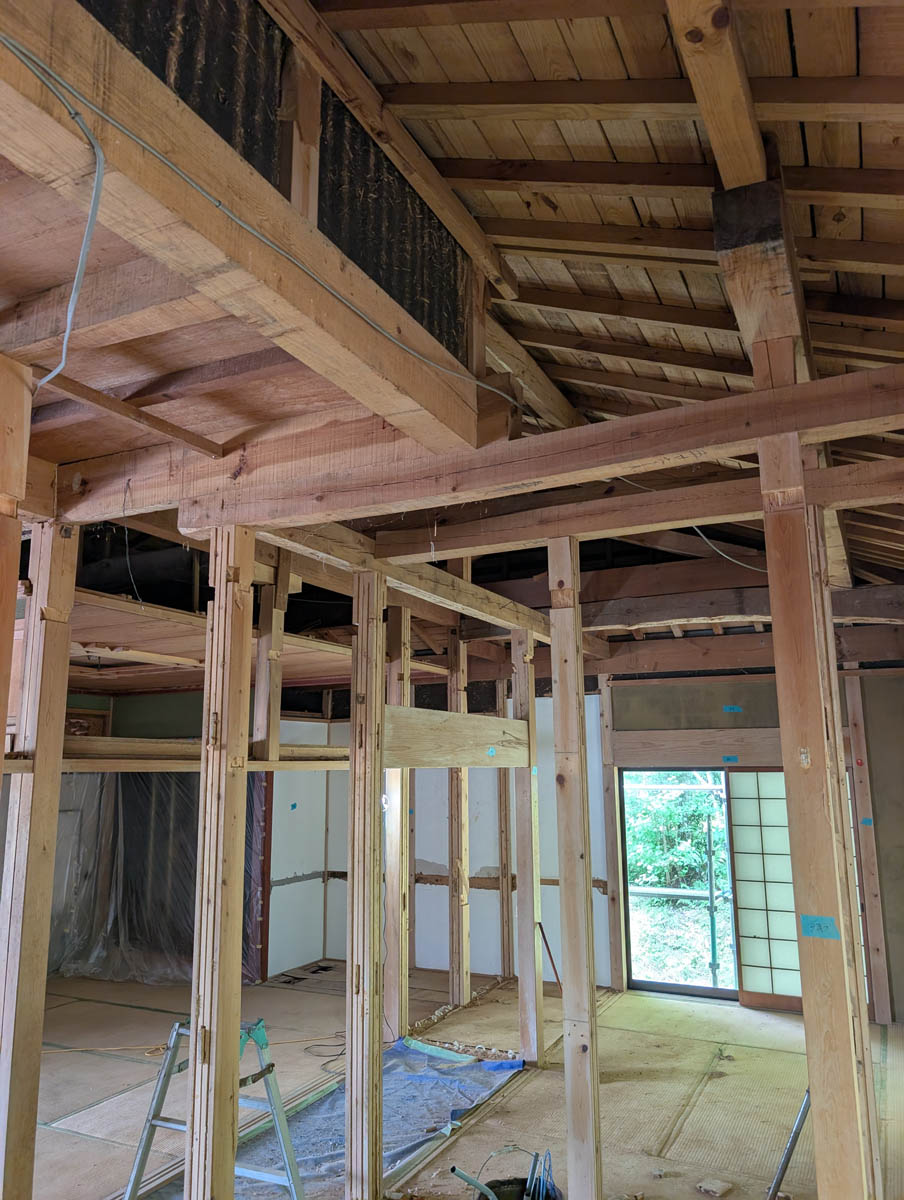 壁や天井が撤去され、建物の骨格全体が見渡せる状態。太い古い梁と新しい間柱が混在している。
